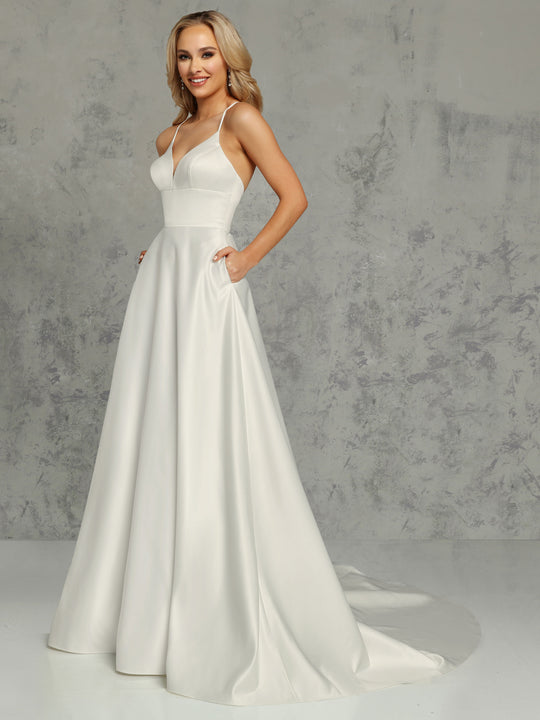 A smiling woman models the Avery Austin "Riley - Tried On Sample," an ivory minimalist satin A-line wedding dress with a fitted bodice, spaghetti straps, pockets, and a flowing train. She stands out against a gray textured background with simply styled light hair.