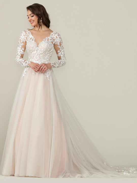 A woman wearing the Avery Austin "Alice - Tried On Sample" long sleeve lace wedding dress in Ivory/Champagne with a deep V-neckline and floral details stands against a light background, smiling and looking to the side.