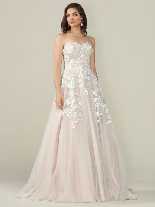 A woman models the Avery Austin "Lydia" wedding dress in Ivory/Blush—a strapless, floor-length tulle gown with a sweetheart neckline and white floral lace appliqué—posed against a plain light background.