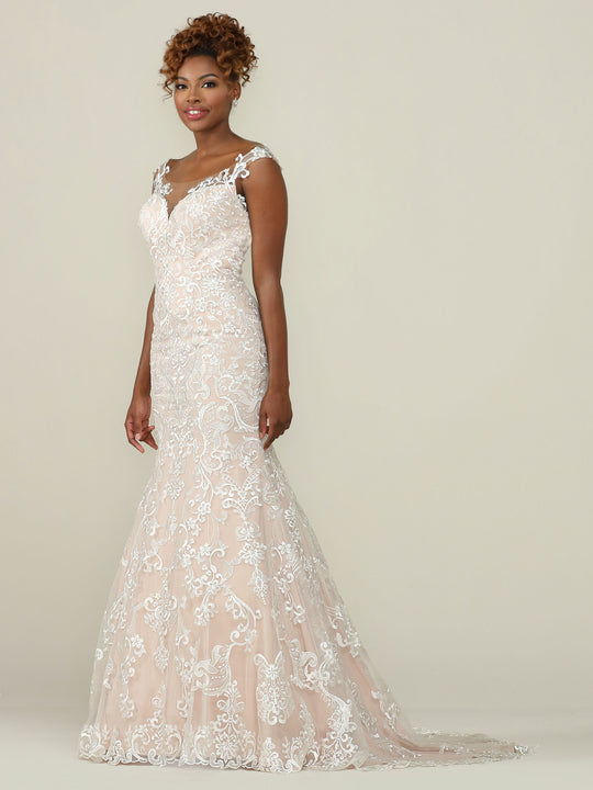 A woman wears the Eliana by Avery Austin—a fitted, sleeveless lace wedding dress with an elegant fit-and-flare silhouette and train—standing against a plain backdrop, smiling softly with her hands by her sides.