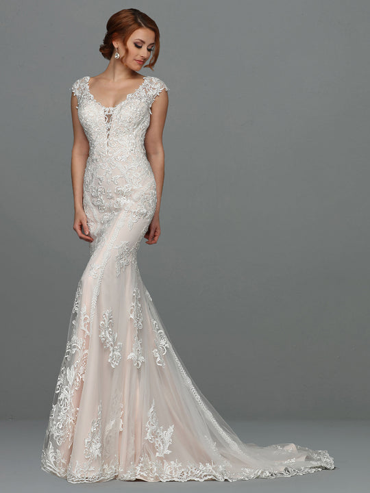 A woman wearing the Avery Austin "Faith" fitted, floor-length lace fit-and-flare wedding dress with a mermaid silhouette and cap sleeves stands against a plain gray background.