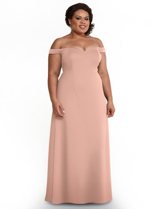 A woman in a mauve, off-the-shoulder, floor-length A-line dress (Avery Austin 83049) stands against a white background, her dark hair styled up and a slight smile on her face.