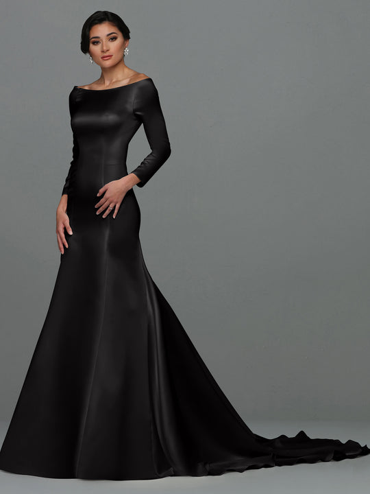 A woman exudes confidence in the Ellie fit-and-flare wedding dress by Avery Austin—a long-sleeve, floor-length black gown with a fitted bodice and flared train—standing against a plain gray background and looking at the camera.