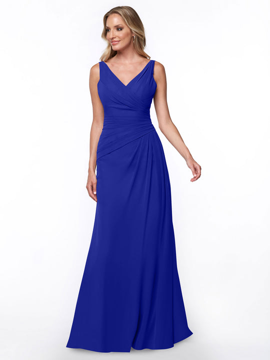 A woman models Avery Austin's 80030 dress in cobalt—a sleeveless, floor-length sheath with a V-neckline and ruched bodice—standing against a plain white background.