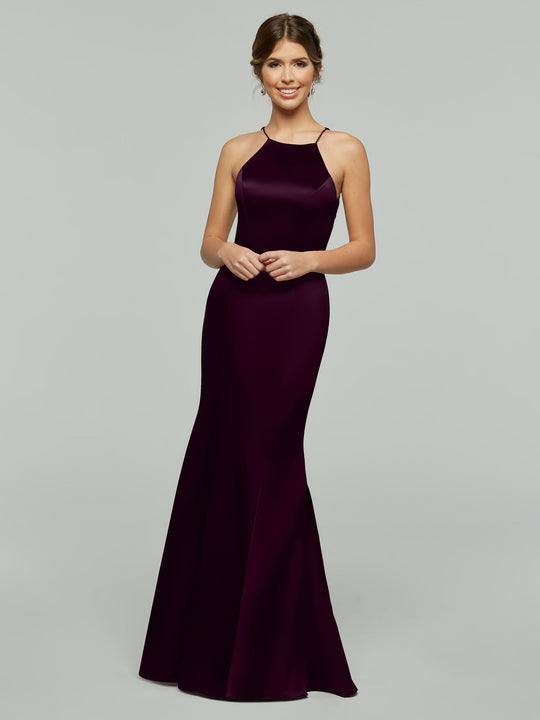 A woman smiles in the Avery Austin 80071, a sleeveless, floor-length deep purple dress with a halter neckline and flared skirt, set against a plain light gray background.