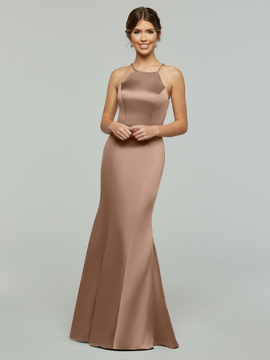 A woman smiles in Avery Austin’s 80071, a sleeveless, floor-length fitted dress with a halter neckline, standing against a plain light gray background.