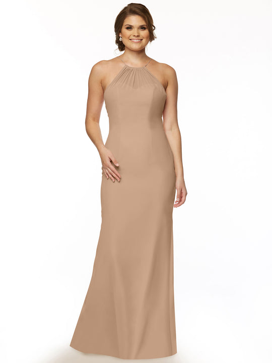 A woman wears Avery Austin 80083, a sleeveless, floor-length buff halter chiffon dress with a keyhole back, posing against a white background with one hand on her hip and the other by her side.