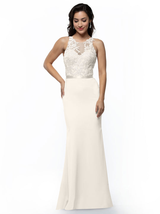 A woman models Avery Austin’s ivory 80095 gown, a floor-length sleeveless dress with an illusion lace bodice and sheer neckline. She stands against a plain white background, smiling gently with one hand on her hip.
