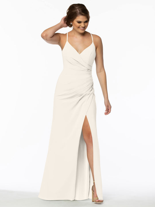 A woman models Avery Austin’s 80114, a sleeveless floor-length chiffon bridesmaid dress featuring thin straps, a V-neckline, ruched waist, and high slit as she smiles against a white background, touching her hair.