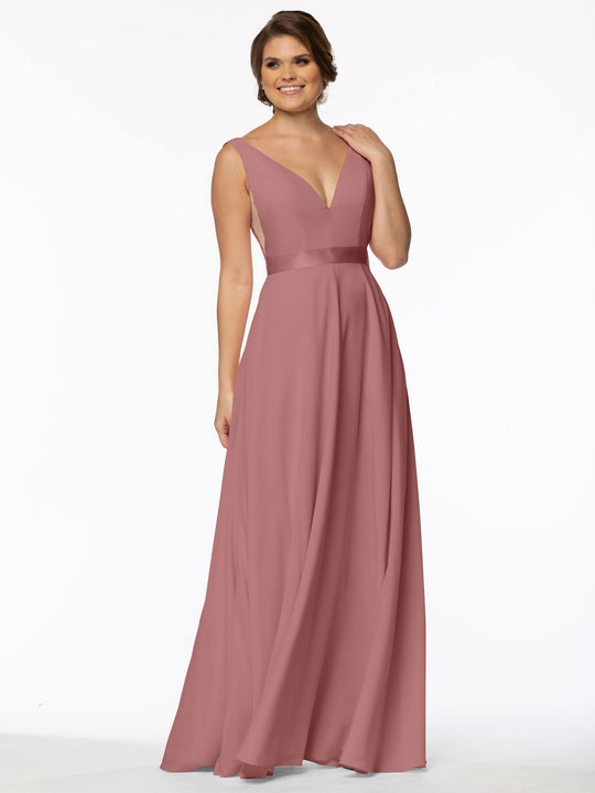 A woman models Avery Austin's 80117, a sleeveless A-line mauve gown with deep V-neck and fitted waist, standing against a white background and smiling gently.
