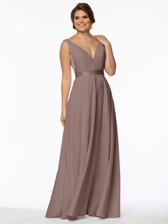 A woman models the Avery Austin 80117, a sleeveless mauve evening gown featuring a deep V-neckline, illusion sides, fitted waist, and flowing A-line silhouette, smiling with one hand in her hair against a white background.