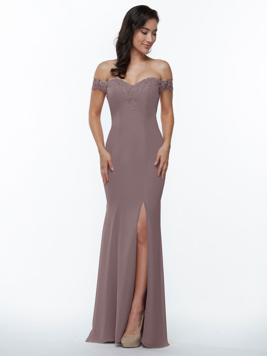 A woman wears Avery Austin's mauve off-the-shoulder bridesmaid dress 80121 with a lace bodice, fitted silhouette, and front slit, paired with beige high heels, standing against a plain white background.