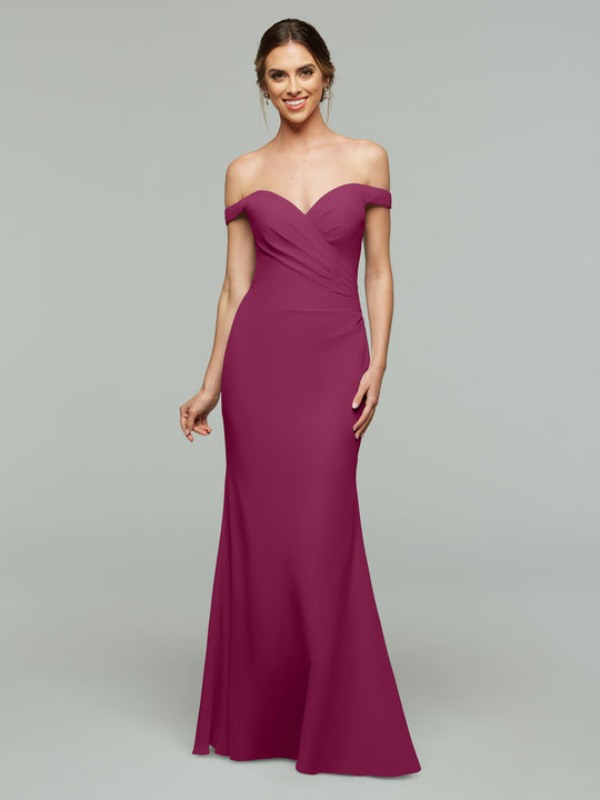 A woman in Avery Austin’s 80122 off-the-shoulder magenta chiffon gown stands against a light gray background, smiling with her hair in a chic updo. The ruched, floor-length bridesmaid dress exudes elegant, timeless style.