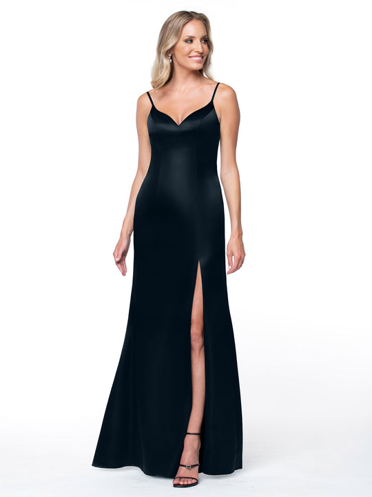 A woman in Avery Austin's 80132—a sleek black evening gown featuring thin straps, a sweetheart neckline, intricate back detail, and a high thigh slit—stands smiling against a plain white background.