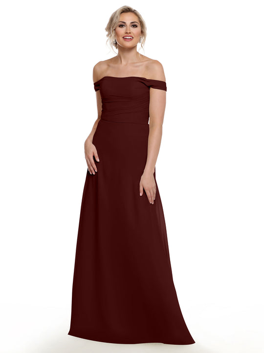A woman in Avery Austin’s 80136, an off-the-shoulder dark red chiffon gown with a floor-length silhouette, stands against a white background, smiling softly with her hands relaxed by her sides.