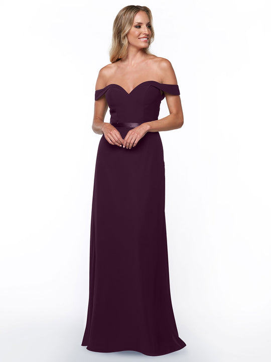 A woman in Avery Austin’s 80145 off-the-shoulder bridesmaid dress in deep purple smiles and looks to the side against a plain white background.