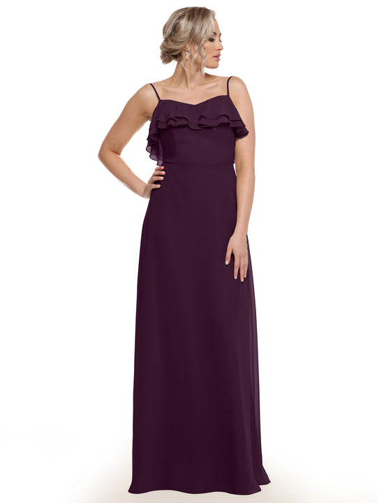 A woman poses against a plain white background in Avery Austin’s floor-length, sleeveless dark purple chiffon A-Line dress (style 80146) featuring tiered chest ruffles. Her elegant updo completes the sophisticated look.