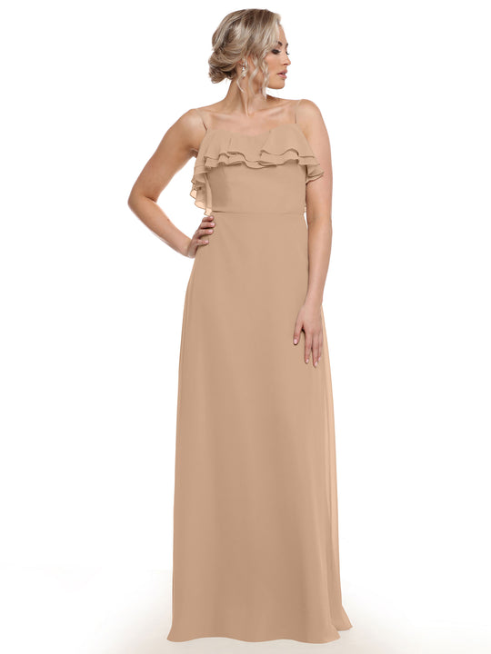 A woman models the Avery Austin 80146, a sleeveless, floor-length beige chiffon A-line dress with tiered chest ruffles, standing against a white background and posing elegantly with one hand on her hip.