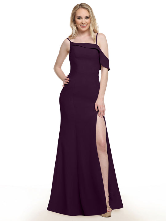 A woman smiles with one hand on her hip, modeling Avery Austin's 80153 floor-length, sleeveless high-slit dress in eggplant against a white background.