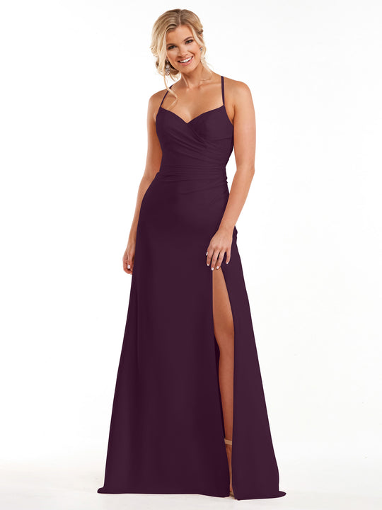 A woman stands smiling against a plain white background, wearing the Avery Austin 80167 bridesmaid dress in Aubergine—a sleeveless, floor-length chiffon gown with thin straps, a sweetheart neckline, ruching, and a high side slit.