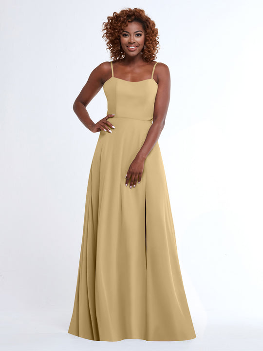 A woman with curly hair smiles in Avery Austin's 80170 sleeveless light gold A-line dress with spaghetti straps, standing against a plain white background.