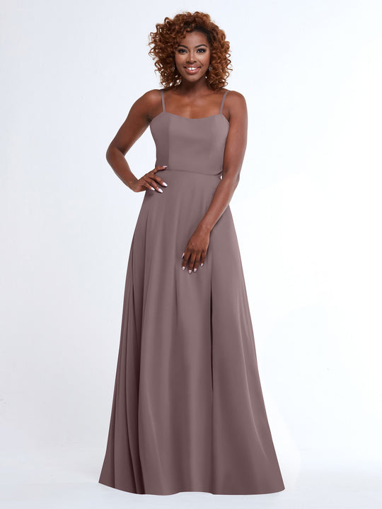 A woman with curly hair poses in the Avery Austin TH-80170, a mauve, flowy floor-length A-Line dress with spaghetti straps, set against a plain white background.