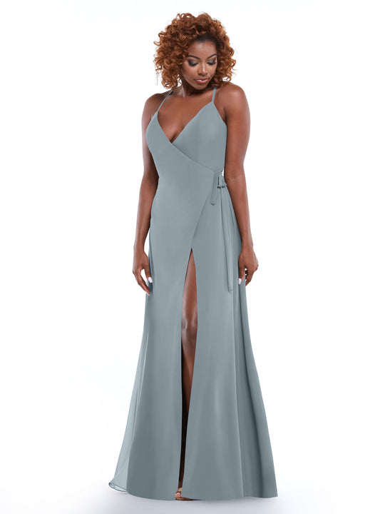 A woman with curly hair stands against a white background wearing Avery Austin style 80171, a light gray sheath dress with a V-neck, wrap bodice, self-tie sash, and high leg slit.