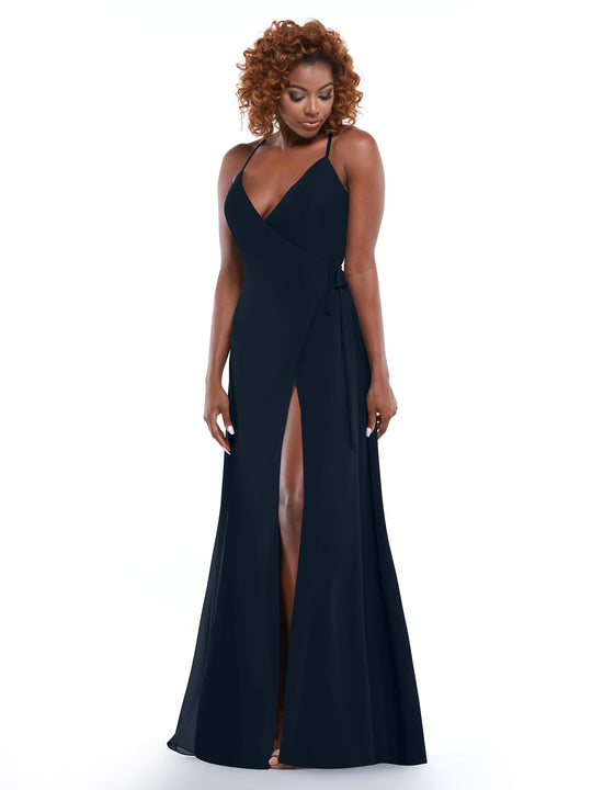 A woman with curly hair models Avery Austin style 80171—a navy blue slit dress with spaghetti straps, deep V-neckline, and self-tie sash—standing against a plain white background.