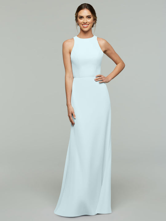 A woman poses against a plain gray background wearing Avery Austin’s 80175, a sleeveless, floor-length light blue A-line dress with a high neckline. She smiles confidently with one hand on her hip.