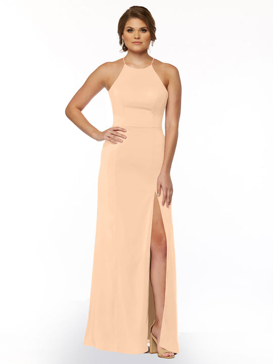 A woman models Avery Austin’s 83026, a peach sheath dress with a halter neck and thigh-high slit. She pairs it with high heels, her light brown hair styled up, posing against a plain white background.