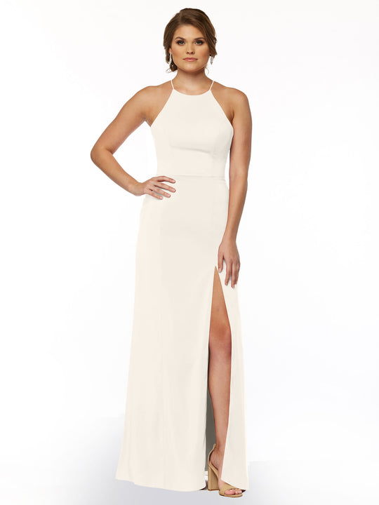 A woman models Avery Austin’s 83026: a sleeveless, floor-length white sheath dress with a high neckline and thigh-high slit, standing in light heels with one hand on her hip against a white background.