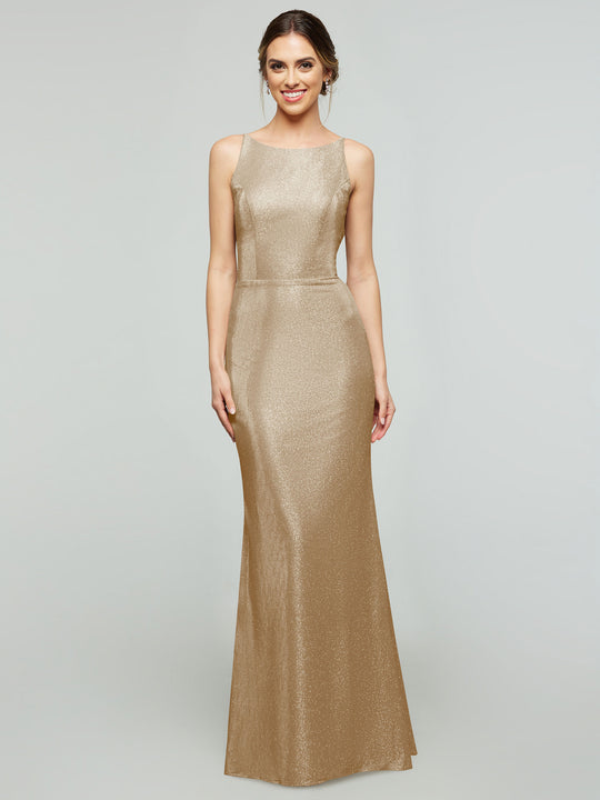 A woman wears the averyaustin 84001 Tried On Sample, a sleeveless, floor-length fitted dress in Glitter Champagne, standing against a light gray background and smiling with her hands at her sides.