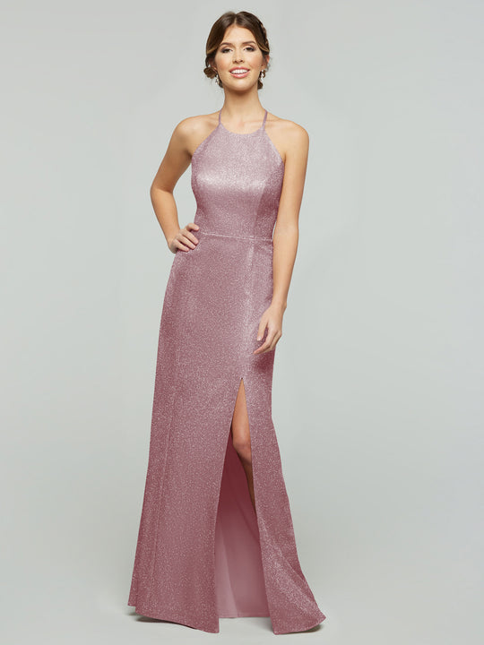 A woman smiles in the averyaustin 84005 - Tried On Sample, a sleeveless, floor-length Glitter Mauve knit sheath dress with a high neckline and thigh-high slit, posing against a plain light gray background.