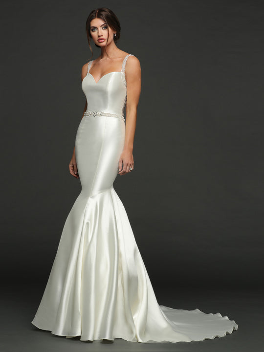 A woman poses in the "Ella - Tried On Sample" by Avery Austin, a fitted ivory mermaid wedding dress with beaded straps, sweetheart neckline, and flared skirt, set against a dark background.