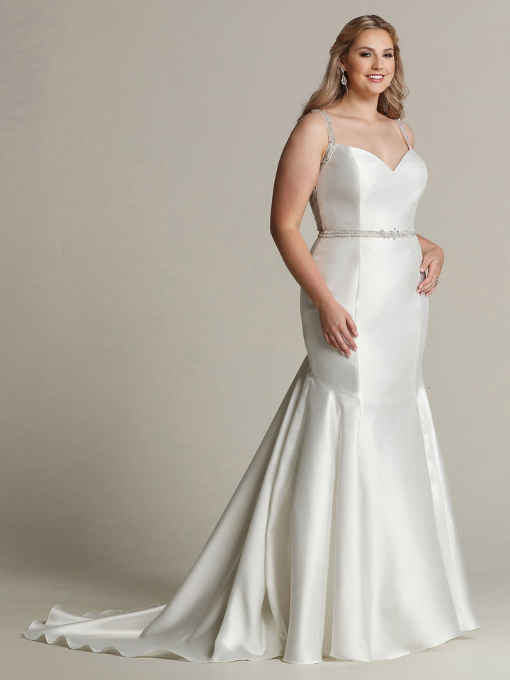 A woman models the Ella - Tried On Sample by Avery Austin: a white sleeveless mikado wedding dress featuring thin straps, a jeweled belt, fitted bodice, flared skirt with small train—perfect for an elegant, timeless bridal look.