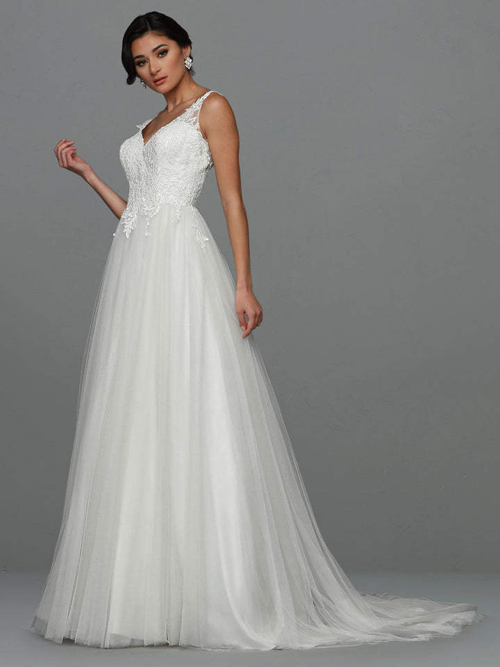 A woman stands against a plain gray background wearing the Avery Austin Skylar wedding dress in Ivory/Ivory, featuring a sleeveless design, lace bodice details, an A-line silhouette, and a flowing tulle floor-length skirt.