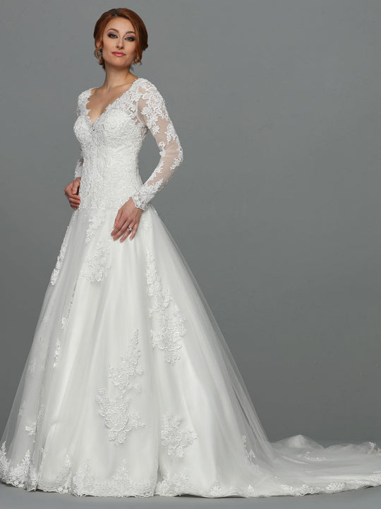 A woman models the Avery Austin Jasmine - Tried On Sample, an ivory A-line wedding dress with long sleeves, lace, floral embroidery, and a long train, standing confidently against a plain gray background.