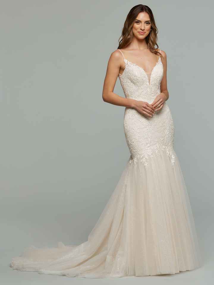 A woman models the averyaustin Imani - Tried On Sample in Ivory/Sand Glitter, featuring a fitted lace bodice, thin straps, and flared tulle skirt, standing against a plain light gray background.