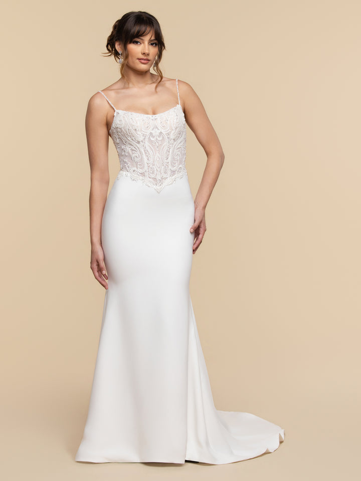 A model wears the TH-Camille ivory fit-and-flare wedding dress, featuring a nude-toned, beaded lace bodice with thin spaghetti straps.