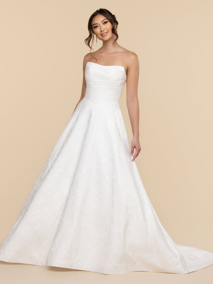 The Cecilia wedding dress by averyaustin is an ivory strapless A-line gown featuring a subtle floral jacquard brocade pattern.