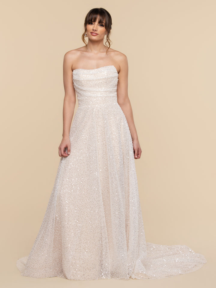 The AveryAustin Auriela wedding gown is a romantic, strapless A-line dress featuring ivory and champagne sequins, a full skirt, and a small train.