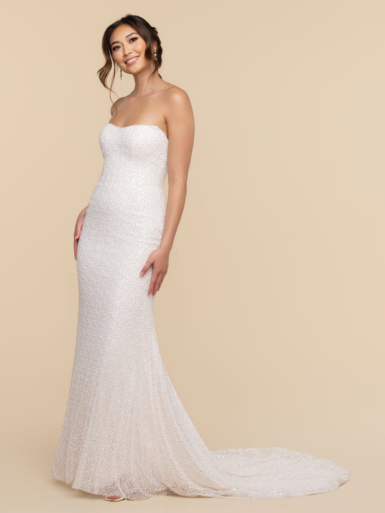 A woman wearing the Alessia floor-length, strapless gown with a scoop neckline, covered in white sequins with a small train.