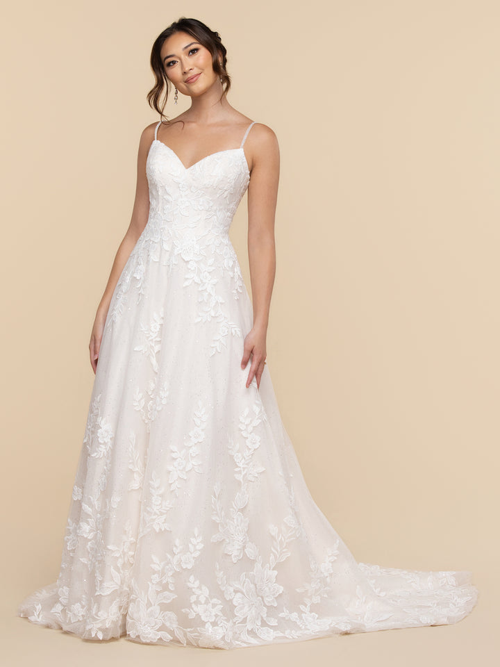 The Elora averyaustin bride wears a sleeveless ivory A-line wedding dress with a floral lace bodice and a sweetheart neckline over a sand-colored skirt.