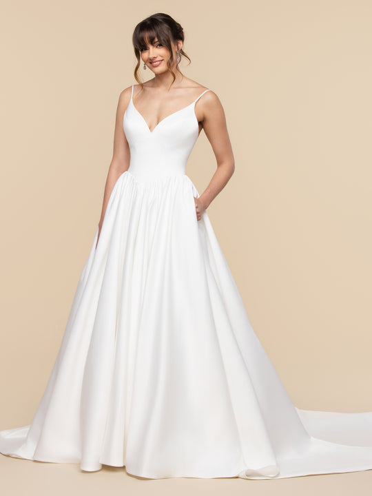 Ivory satin Madeleine A-line wedding dress with a V-neckline, thin straps, and a full, ruched skirt with pockets.