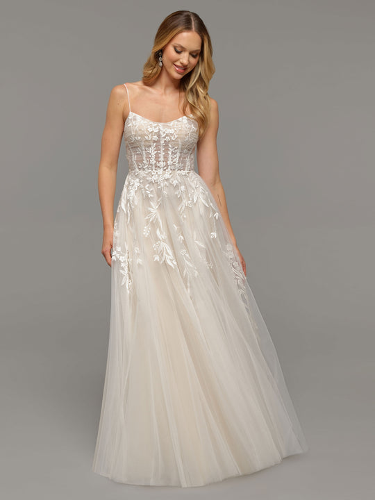 A woman models the averyaustin Kendall wedding dress—a sleeveless, floor-length ivory tulle gown with floral embroidery, lace appliques, and thin spaghetti straps—against a plain gray background.