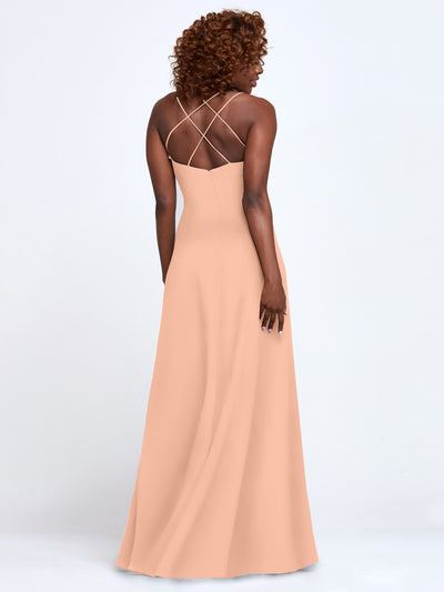 A woman with curly hair models Avery Austin's 83045—a long, peach A-line dress with thin criss-cross spaghetti straps and an open back—facing away from the camera against a plain white background.