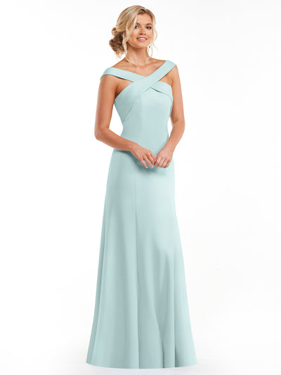 A woman in the Avery Austin 83048 floor-length sky blue A-line dress with off-the-shoulder sleeves and a criss-cross neckline stands smiling against a white background, her hair styled in an elegant updo.