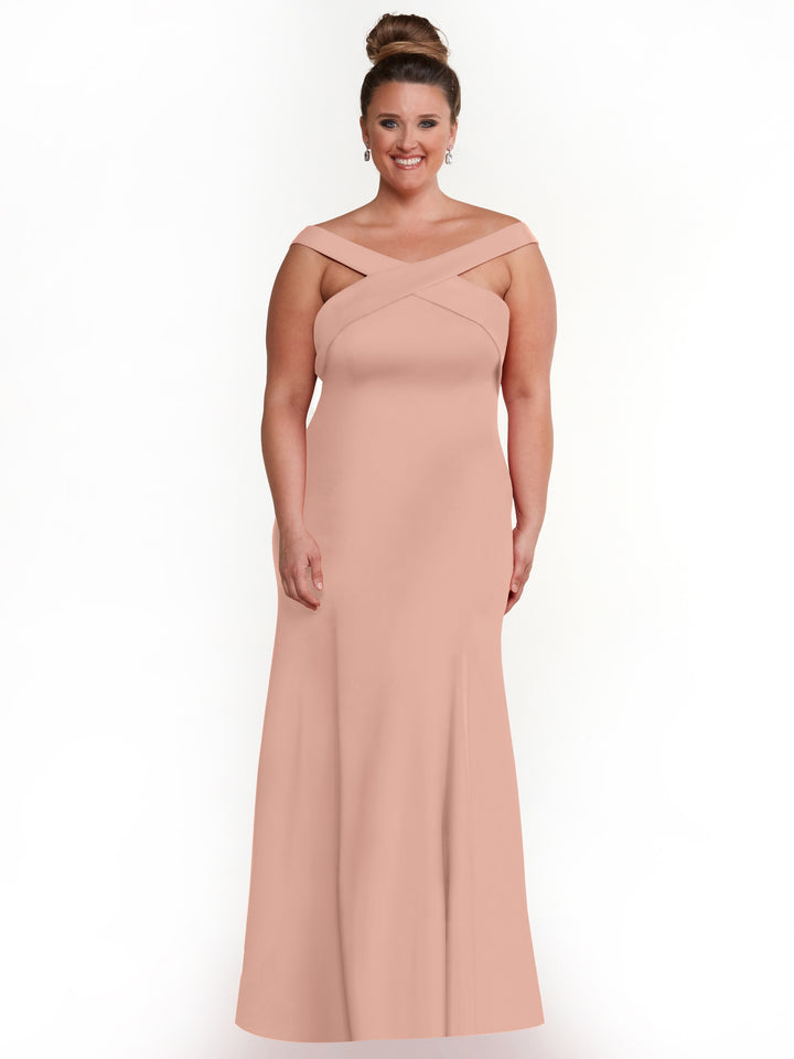 A woman in a mauve, off-the-shoulder A-Line dress (Style 83048) by Avery Austin, featuring a criss-cross neckline, smiles with her hair in a high bun against a white background.
