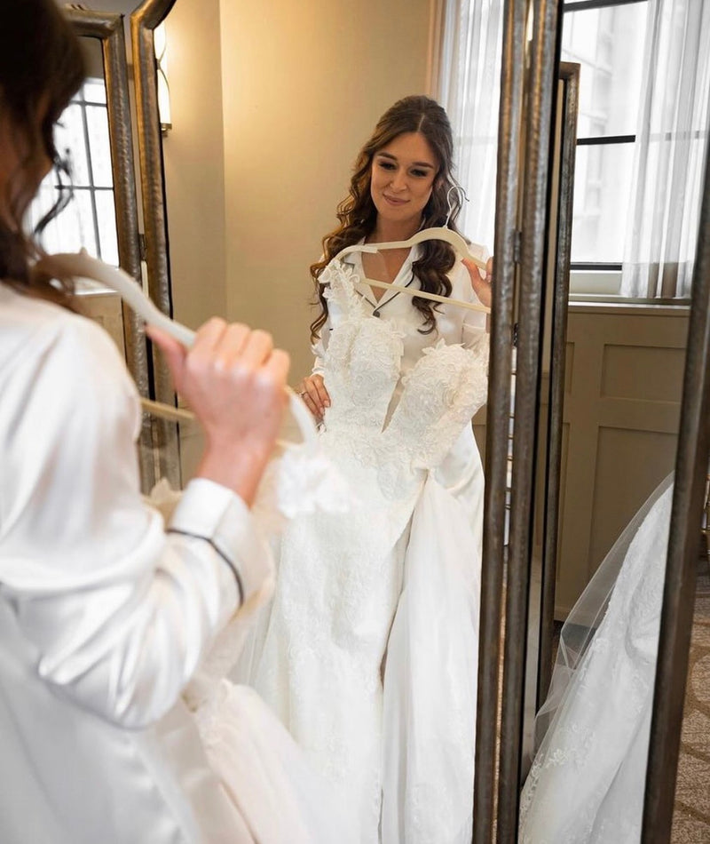 Woman trying on a wedding dress in front of a mirror.