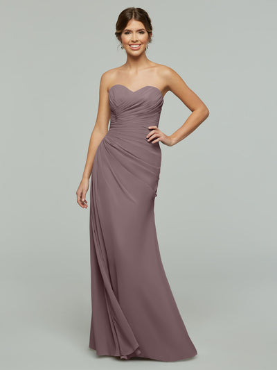 A woman poses against a plain light grey background wearing the Avery Austin 80028, a mauve floor-length chiffon dress featuring a sweetheart neckline and ruched detailing.